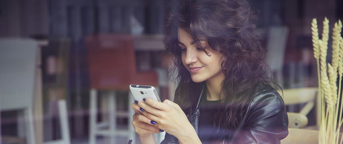 A young woman of color looking at a phone 